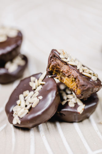 rohveganer snack in reese's form. bestehend aus zwei schichten: cashews und sonnenblumenkernmus. überzogen mit schokolade und mit sonnenblumenkernen dekoriert