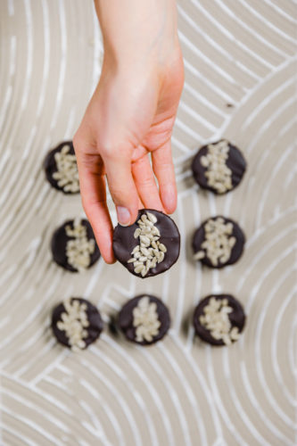 rohveganer snack in reese's form. bestehend aus zwei schichten: cashews und sonnenblumenkernmus. überzogen mit schokolade und mit sonnenblumenkernen dekoriert