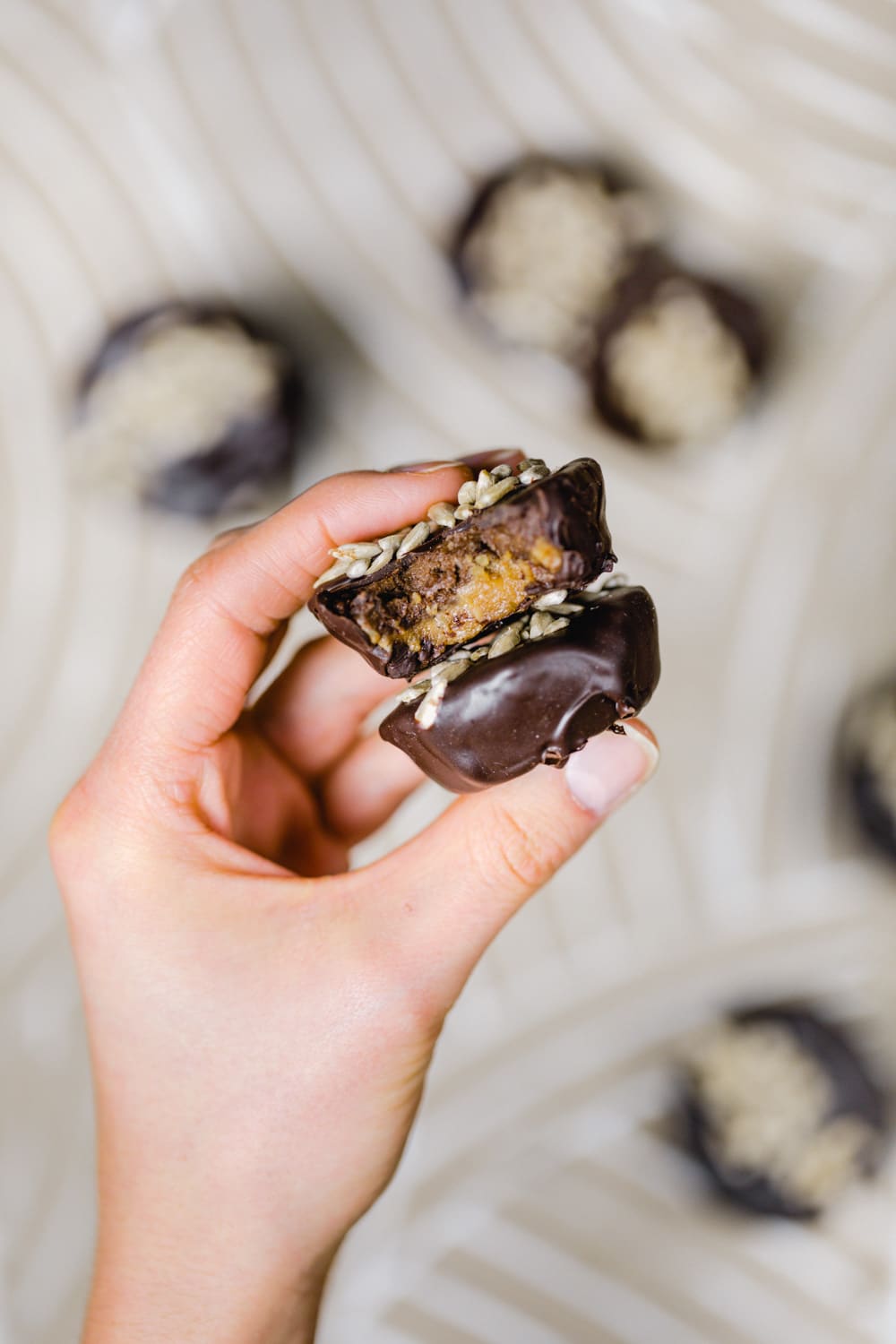 rohveganer snack in reese's form. bestehend aus zwei schichten: cashews und sonnenblumenkernmus. überzogen mit schokolade und mit sonnenblumenkernen dekoriert